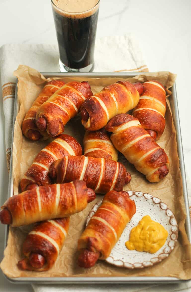 Side view of a tray of pretzel dogs and a beer.