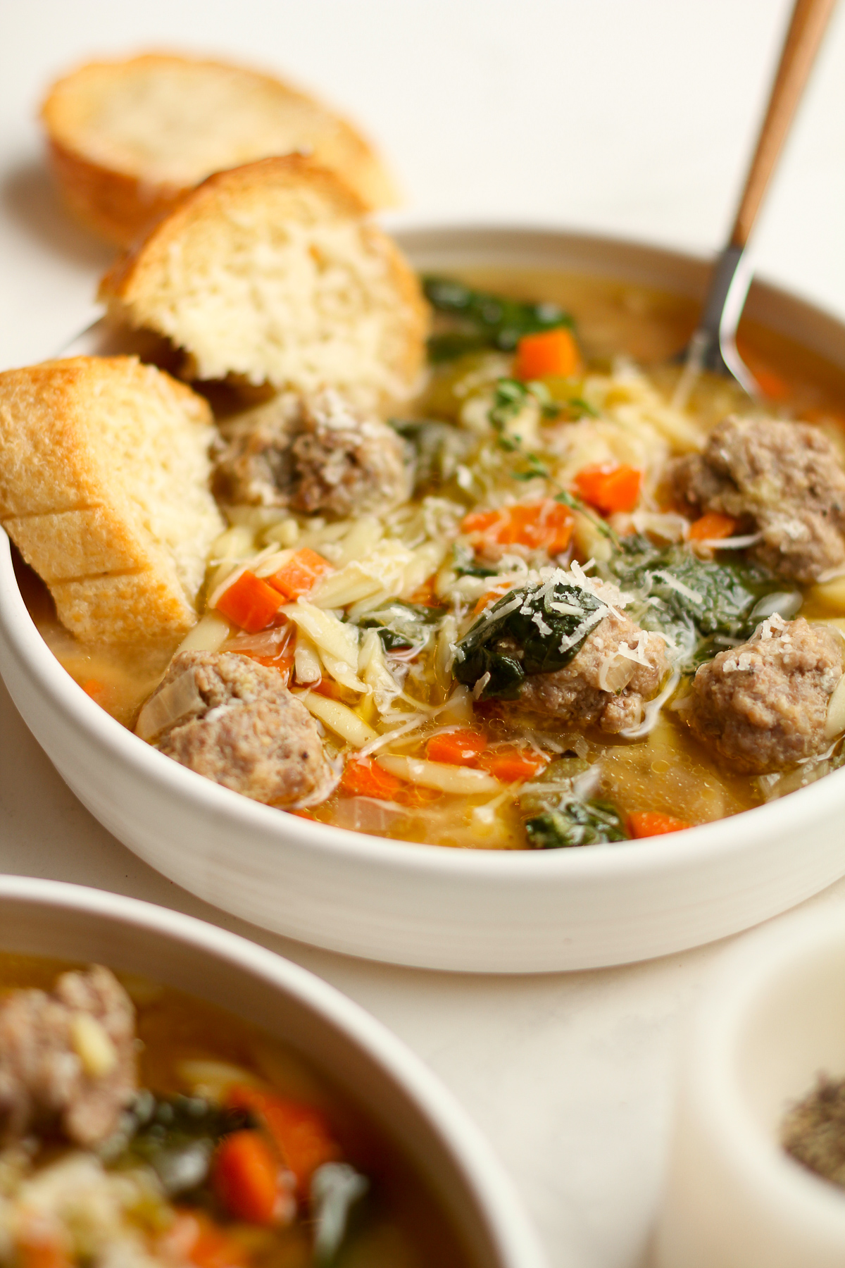 Side view of two bowls of meatball wedding soup.