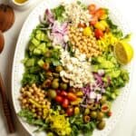 A large platter of Mediterranean chopped salad, with a jar of dressing.