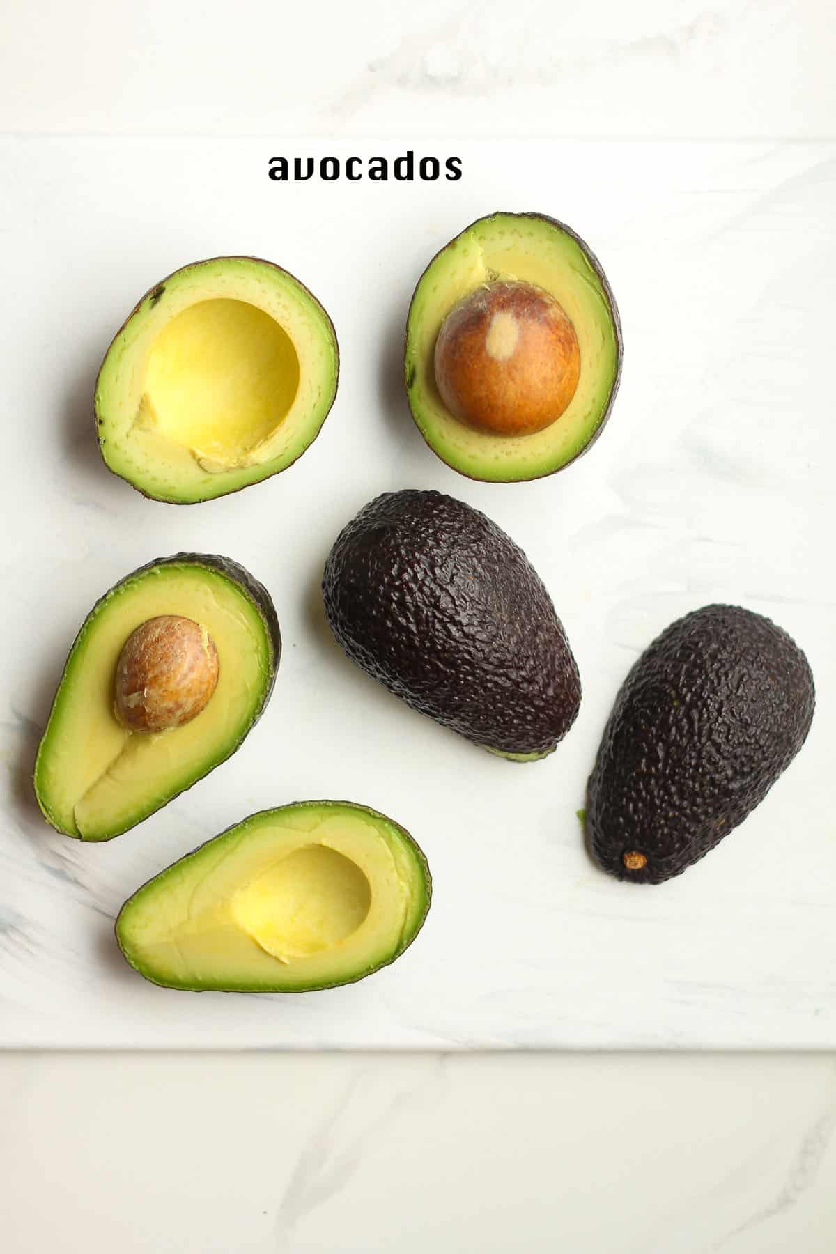 Halved avocados on a white board.