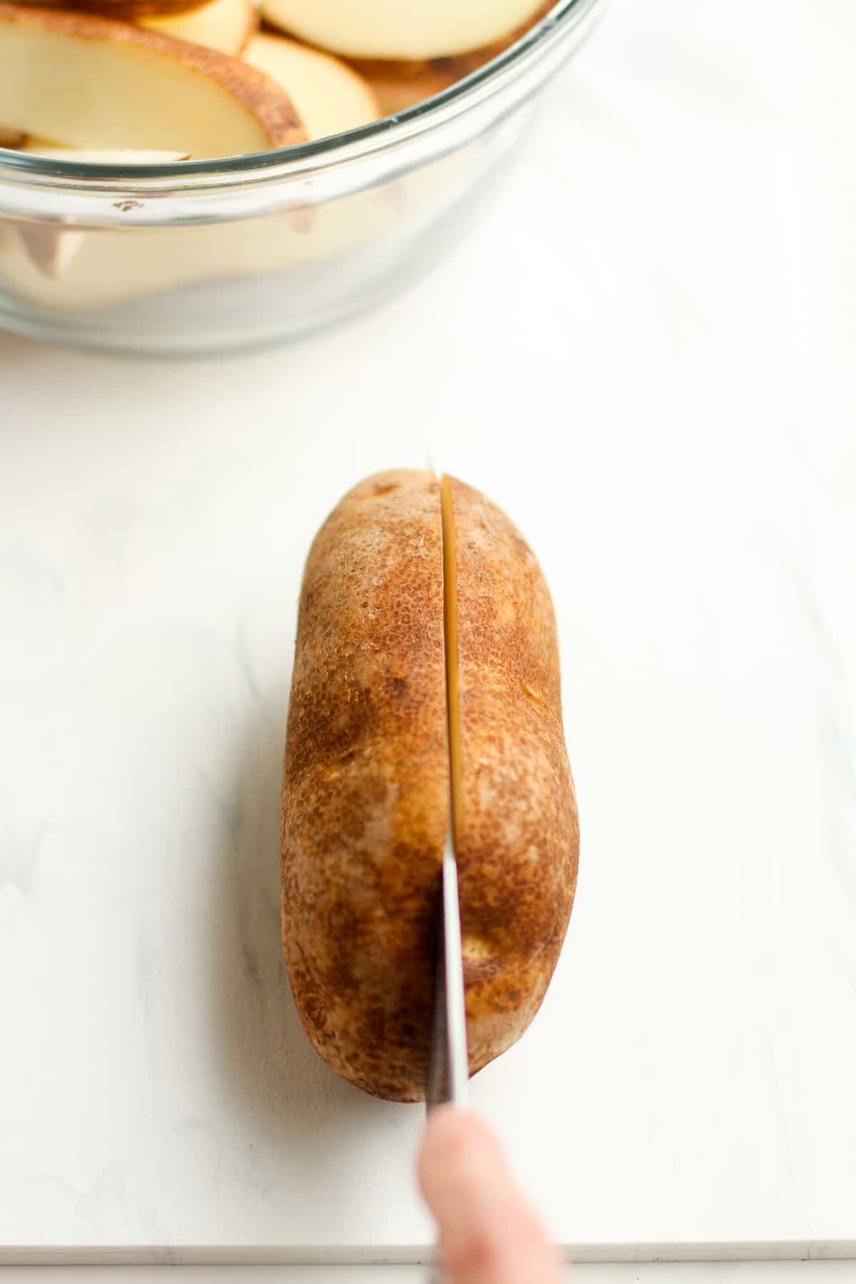 A knife slicing the potato in half.