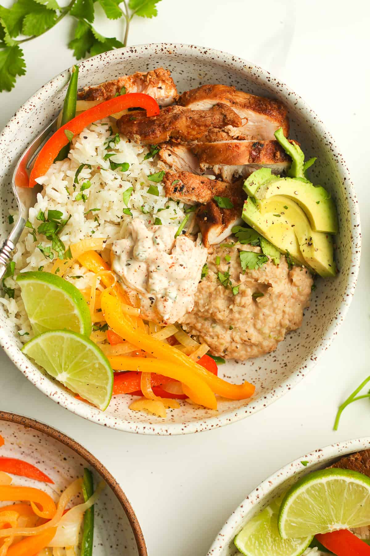 Closeup on a chipotle chicken bowl with lime wedges.