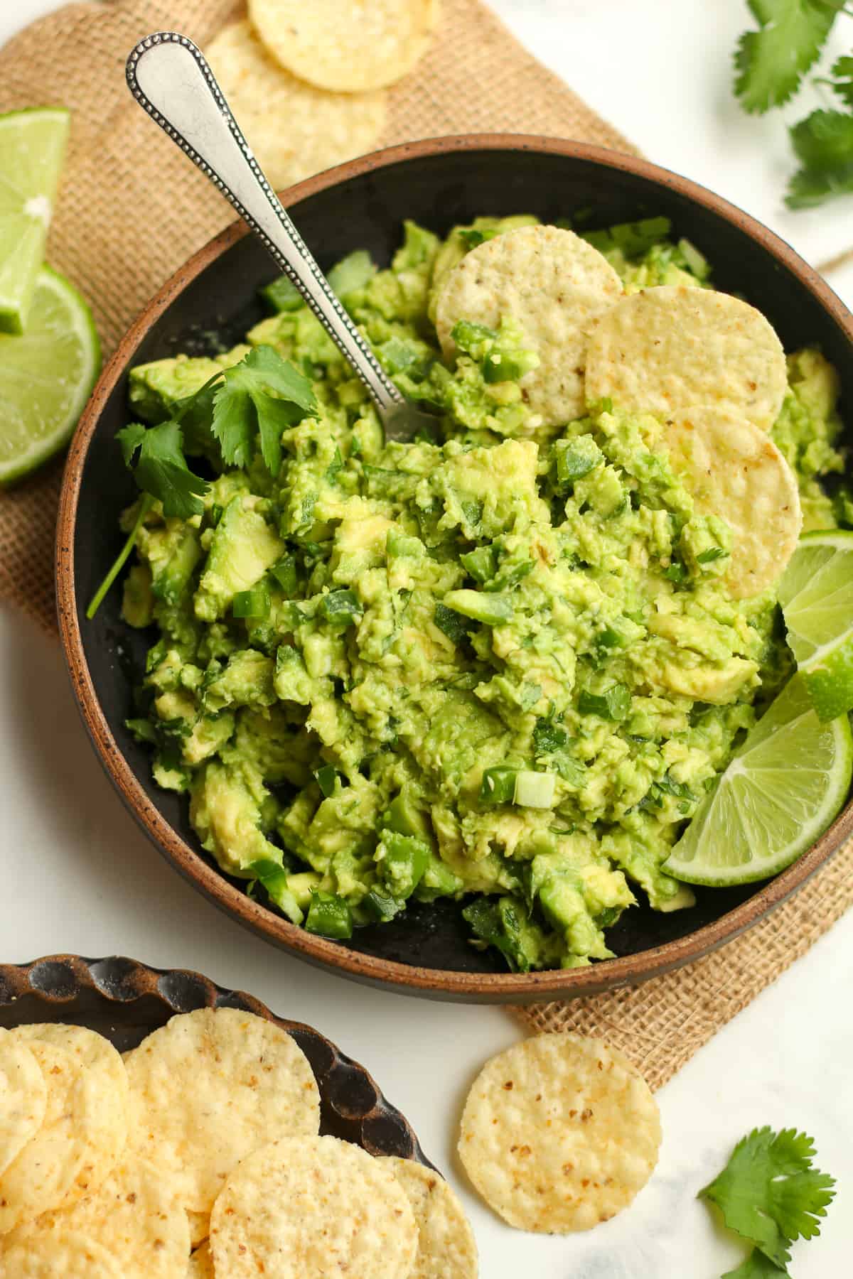 Closeup on a bowl of guac and chips, with a spoon.