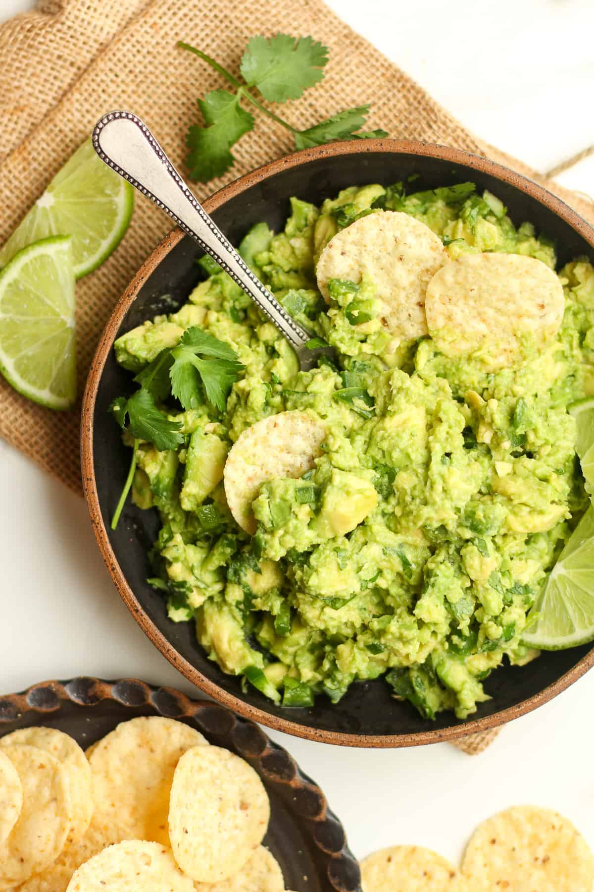 A bowl of guac with chips inside the guac and a spoon.