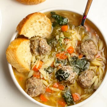 A bowl of Italian Wedding Soup with turkey meatballs and some crusty bread.