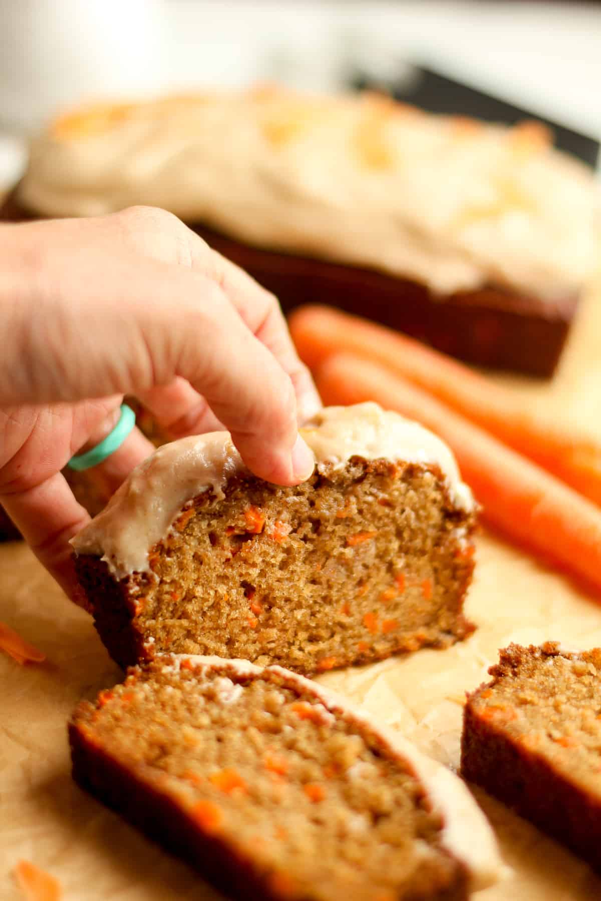 My hand picking up a piece of moist carrot cake bread.