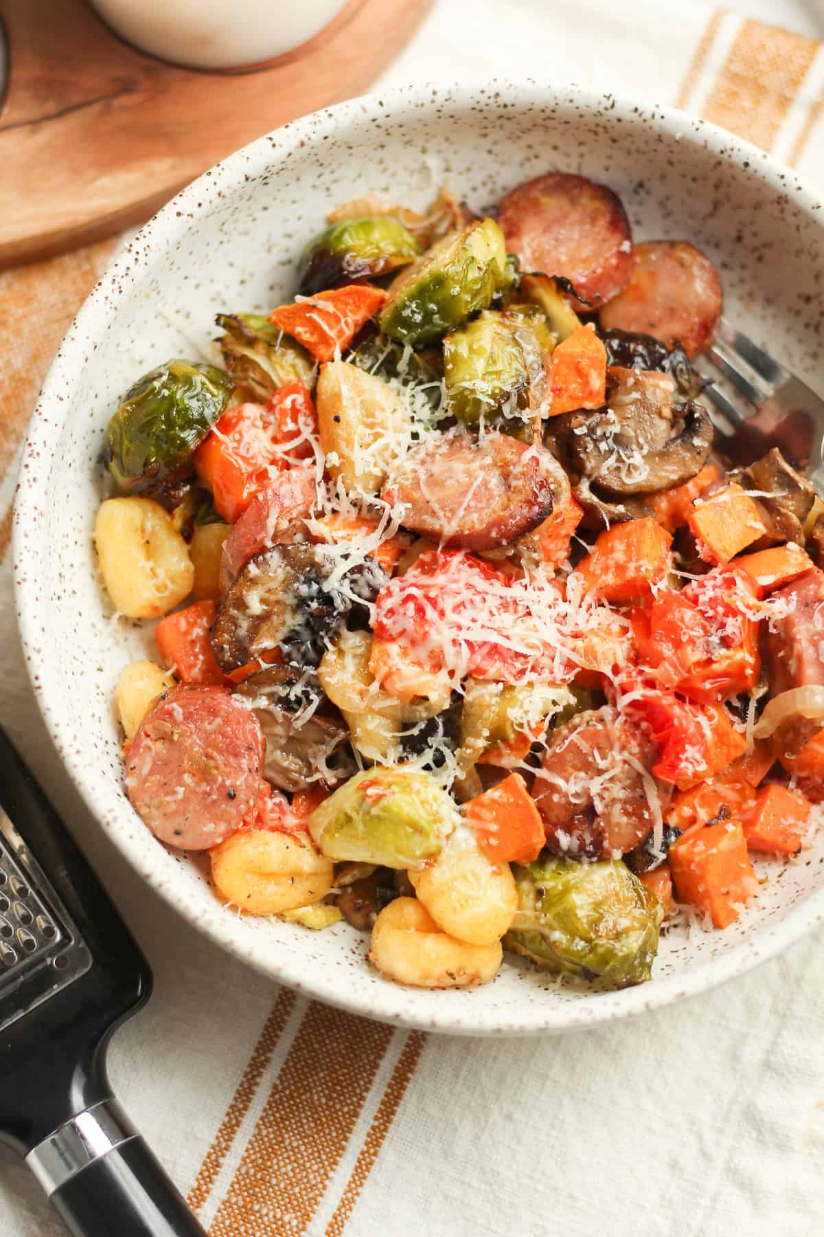 A serving of gnocchi and roasted vegetables with a fork.