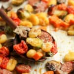 Side view of a spoonful of gnocchi and roasted veggies on a sheet pan.