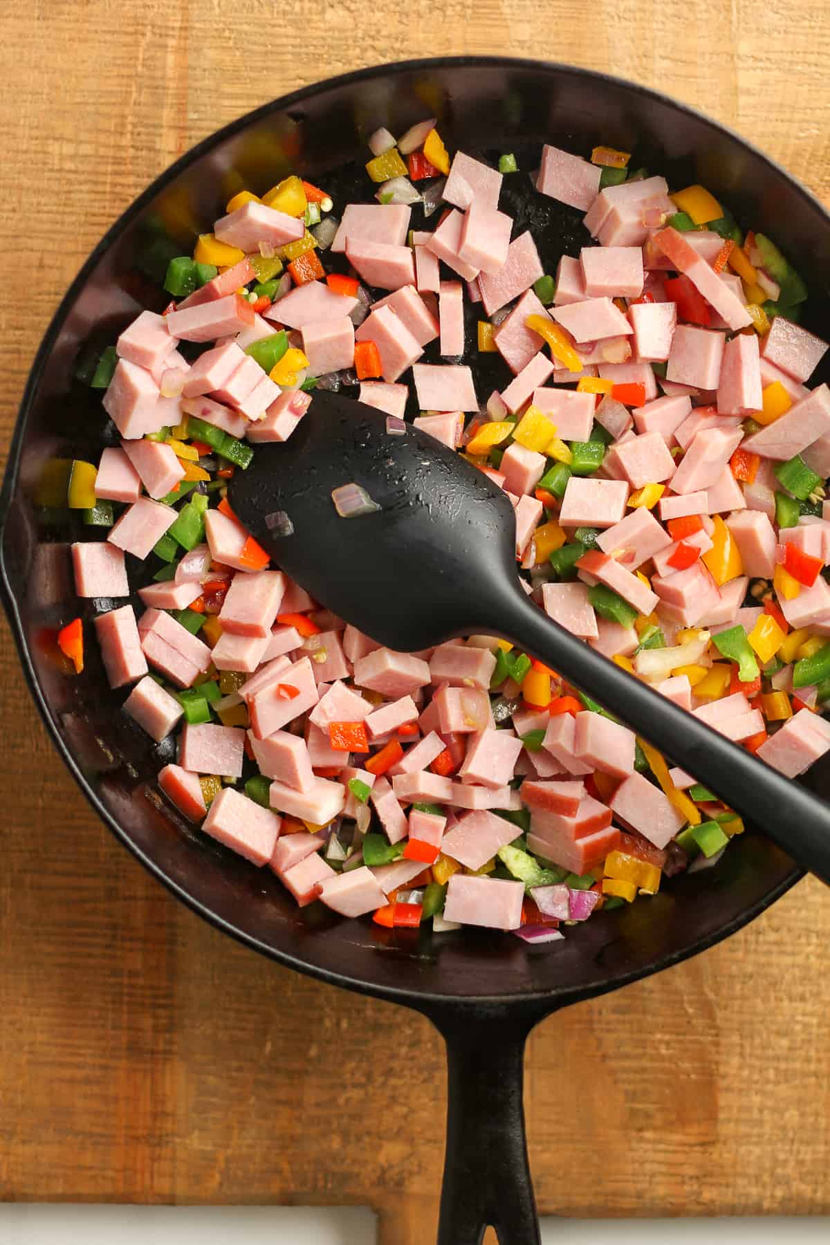 A skillet with the sautéed veggies and ham.