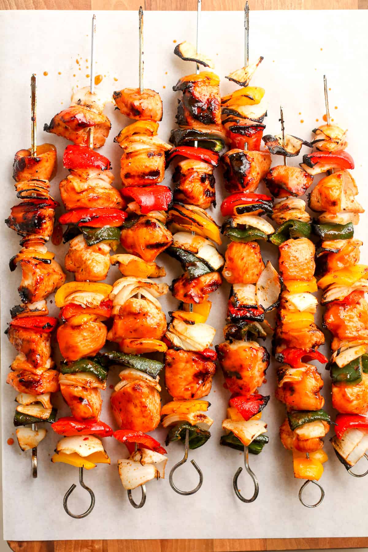 The honey sriracha chicken kabobs on a wooden board with white parchment.