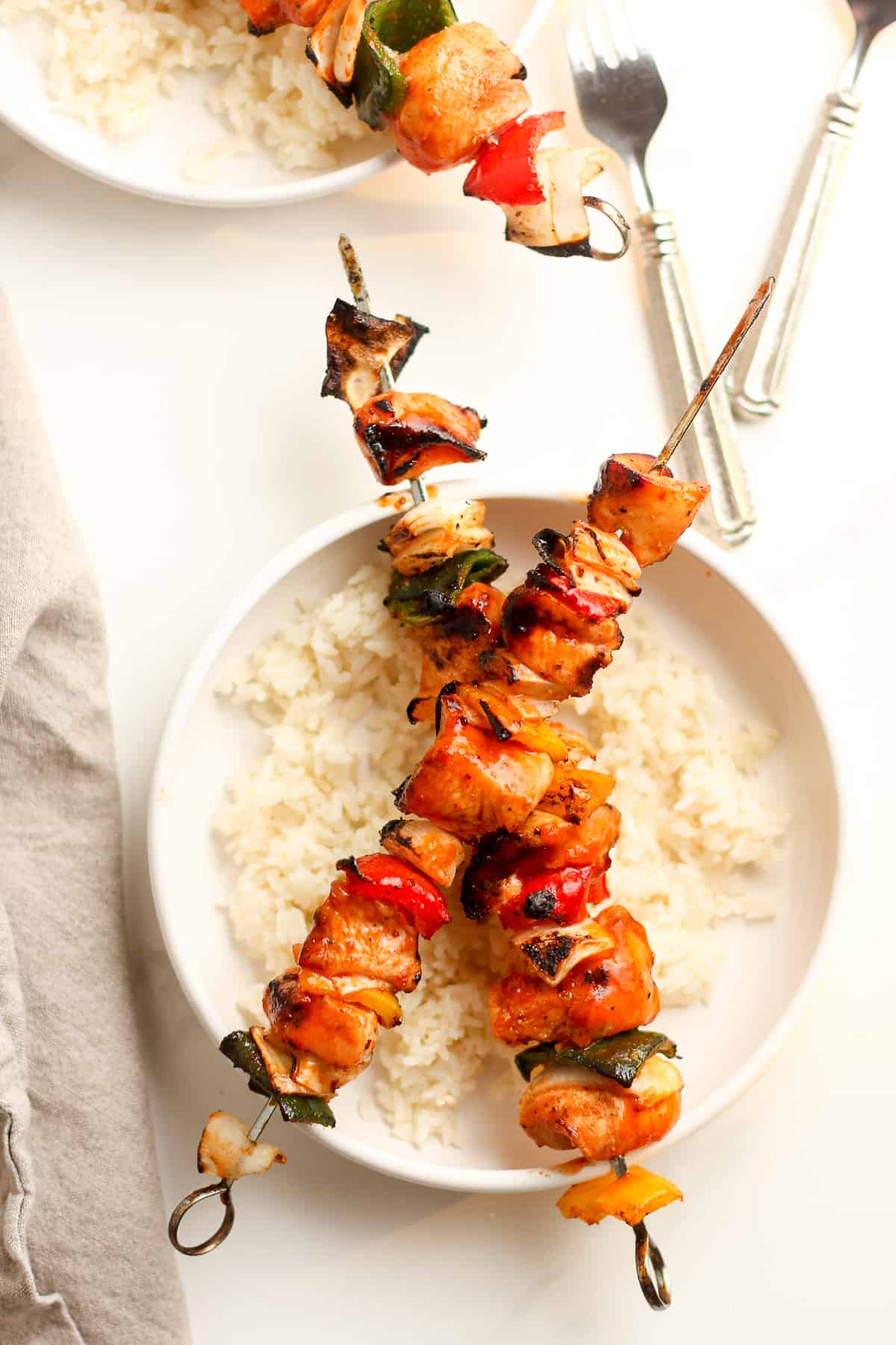A serving of rice with two chicken kabobs with honey sriracha sauce.