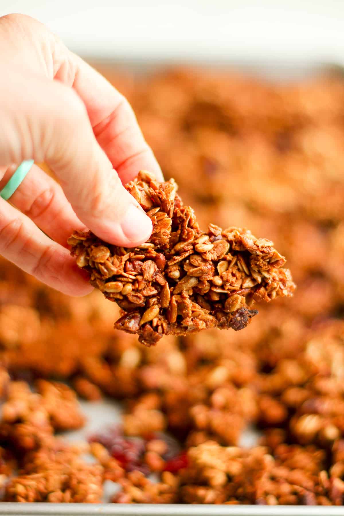 My hand holding a large piece of maple pecan granola.