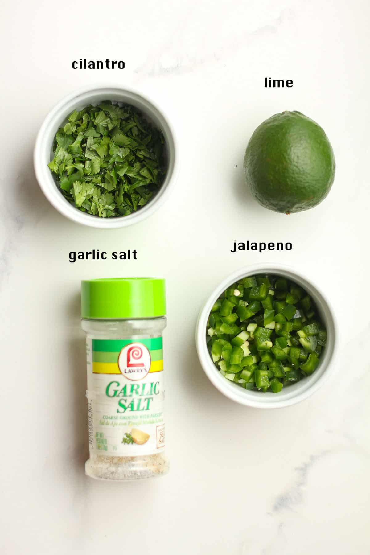 The other ingredients for the guacamole including cilantro, lime, jalapeño, and garlic salt.