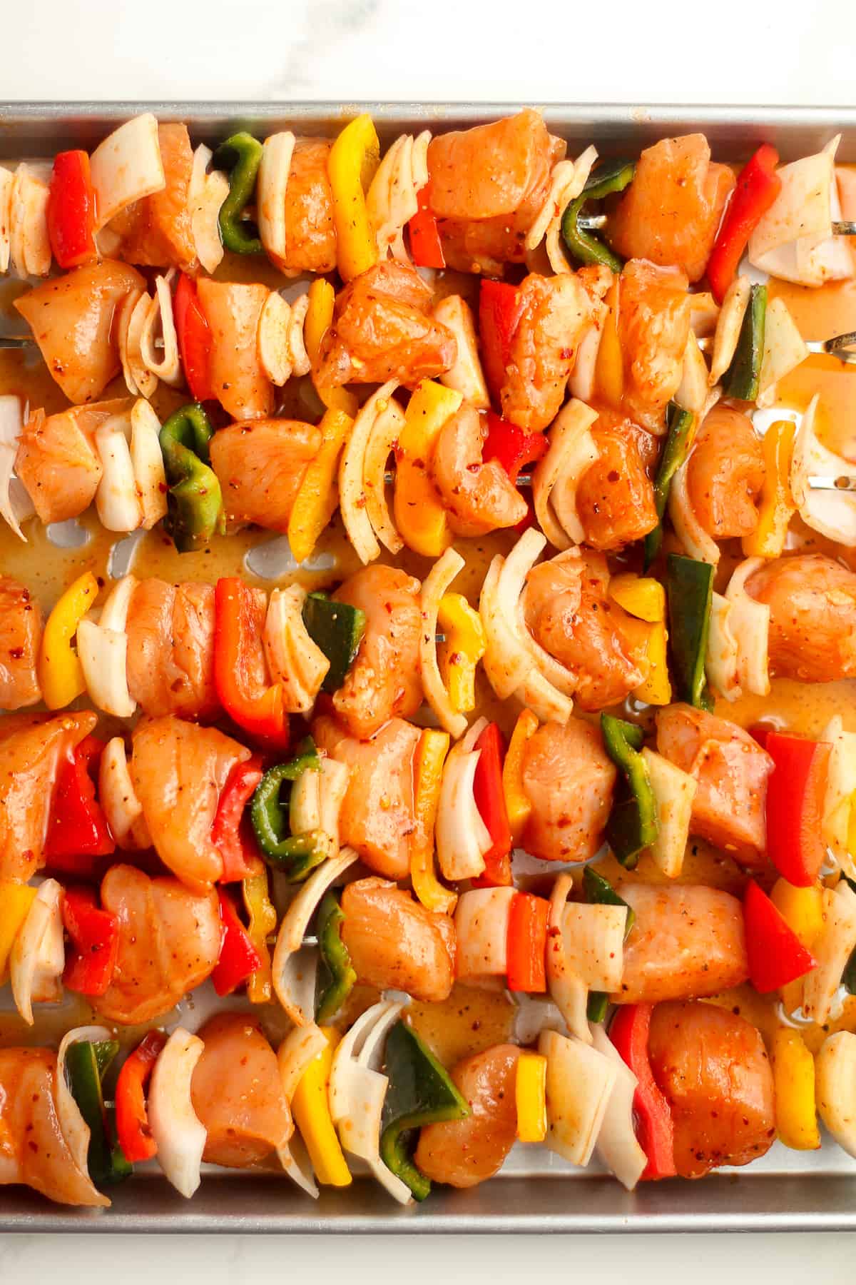 The raw kabobs, prepared for grilling with alternating chicken, onion, and peppers.