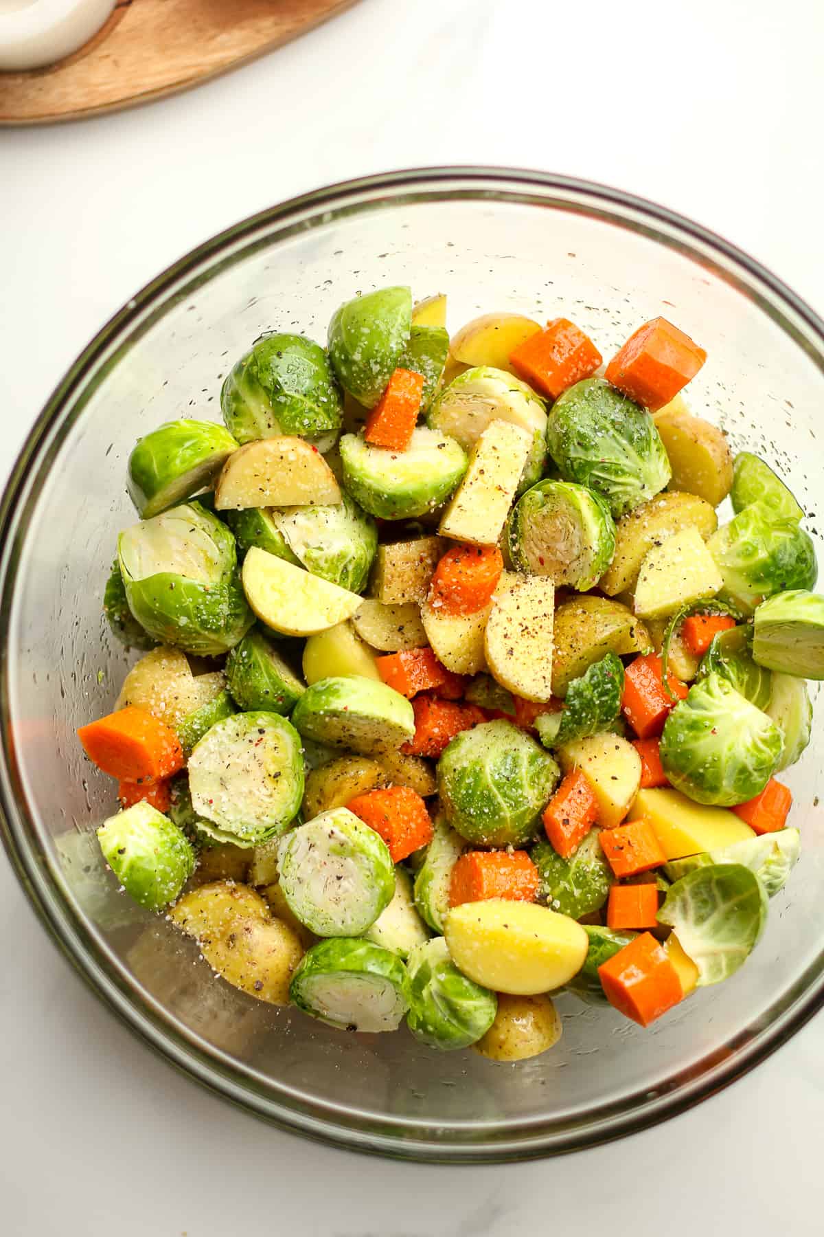 A bowl of chopped veggies with olive oil and salt, and pepper.
