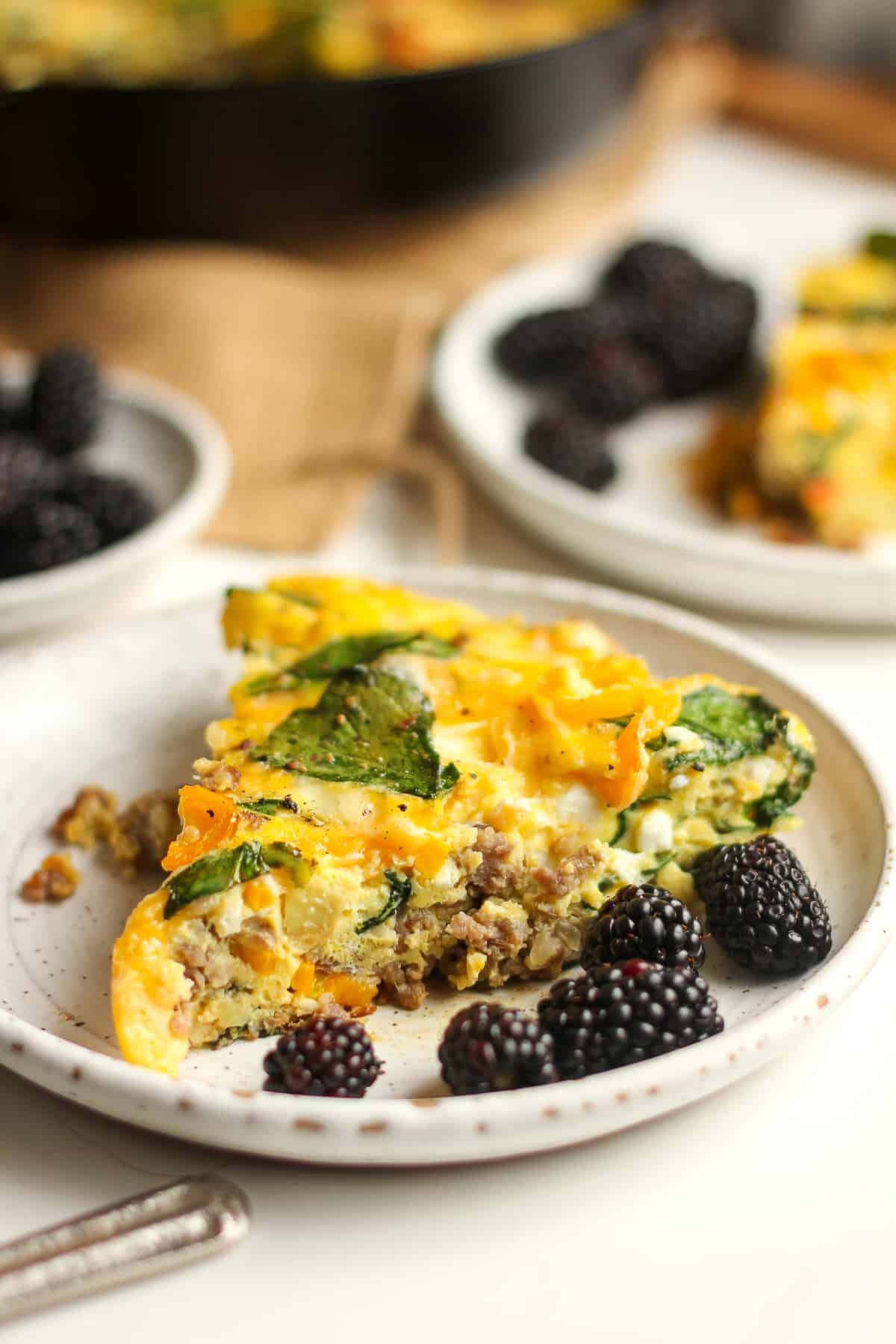Side view of a large slice of frittata with berries.