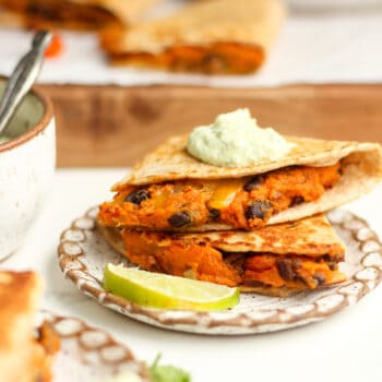 Side view of a plate of sweet potato black bean quesadillas with Avocado Crema.
