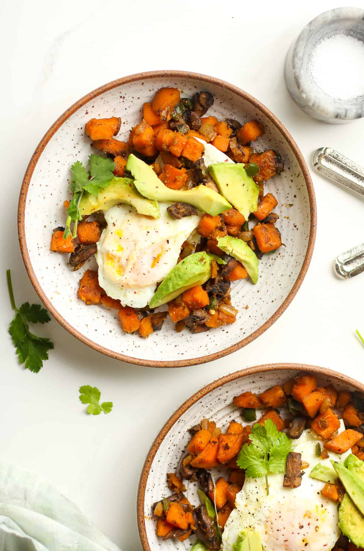 Two bowls of the sweet potato hash with the soft eggs on top.
