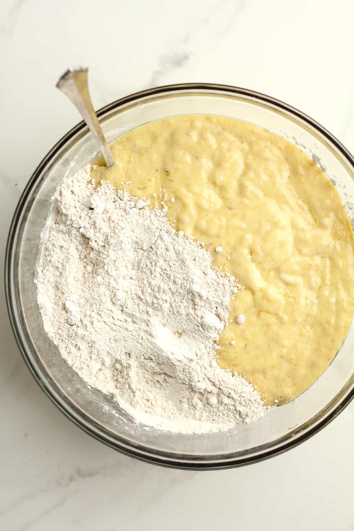 A bowl of the banana cake batter with the flour on top.