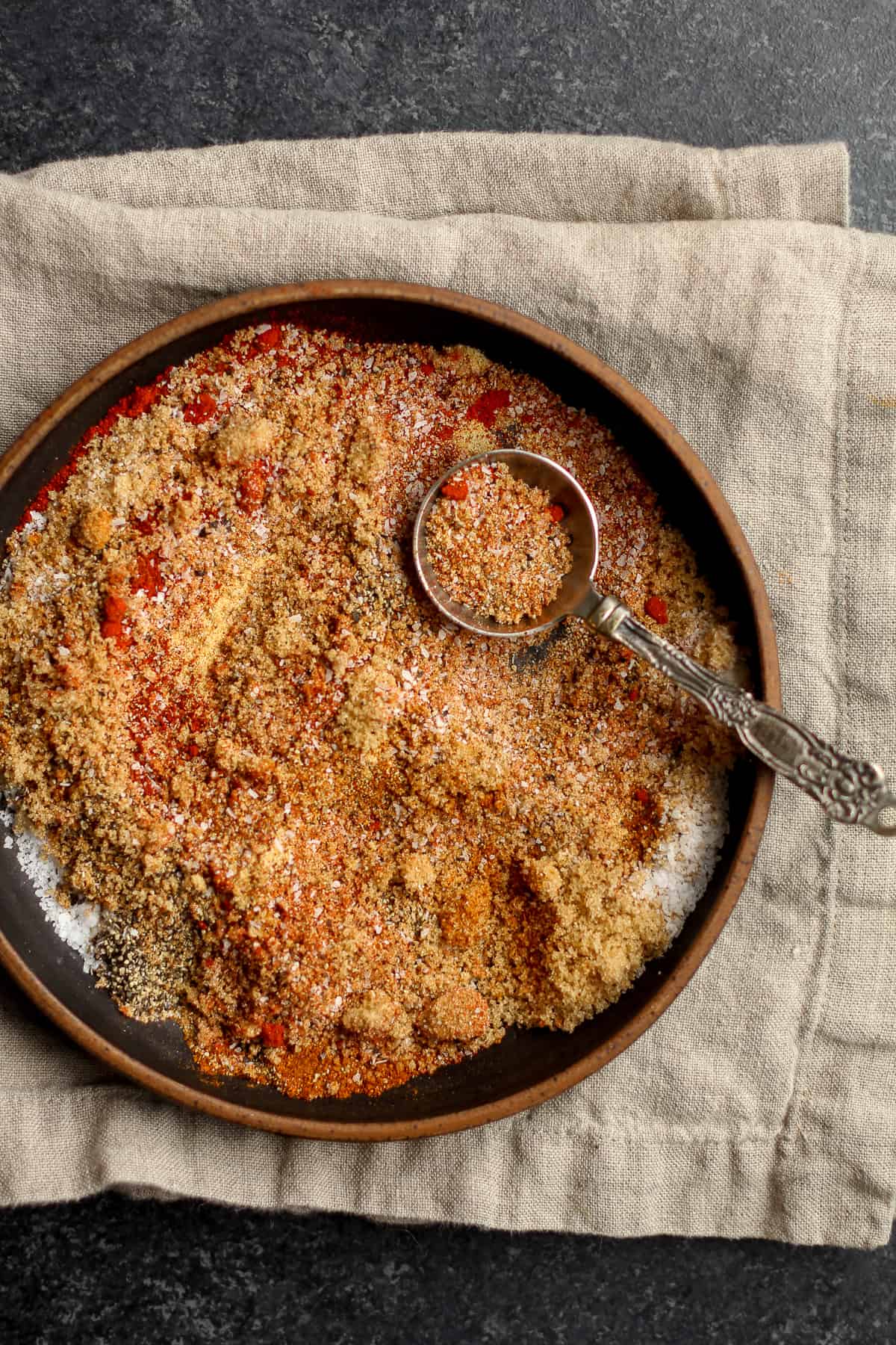 The bowl of dry rub partially mixed together, with a tablespoon.