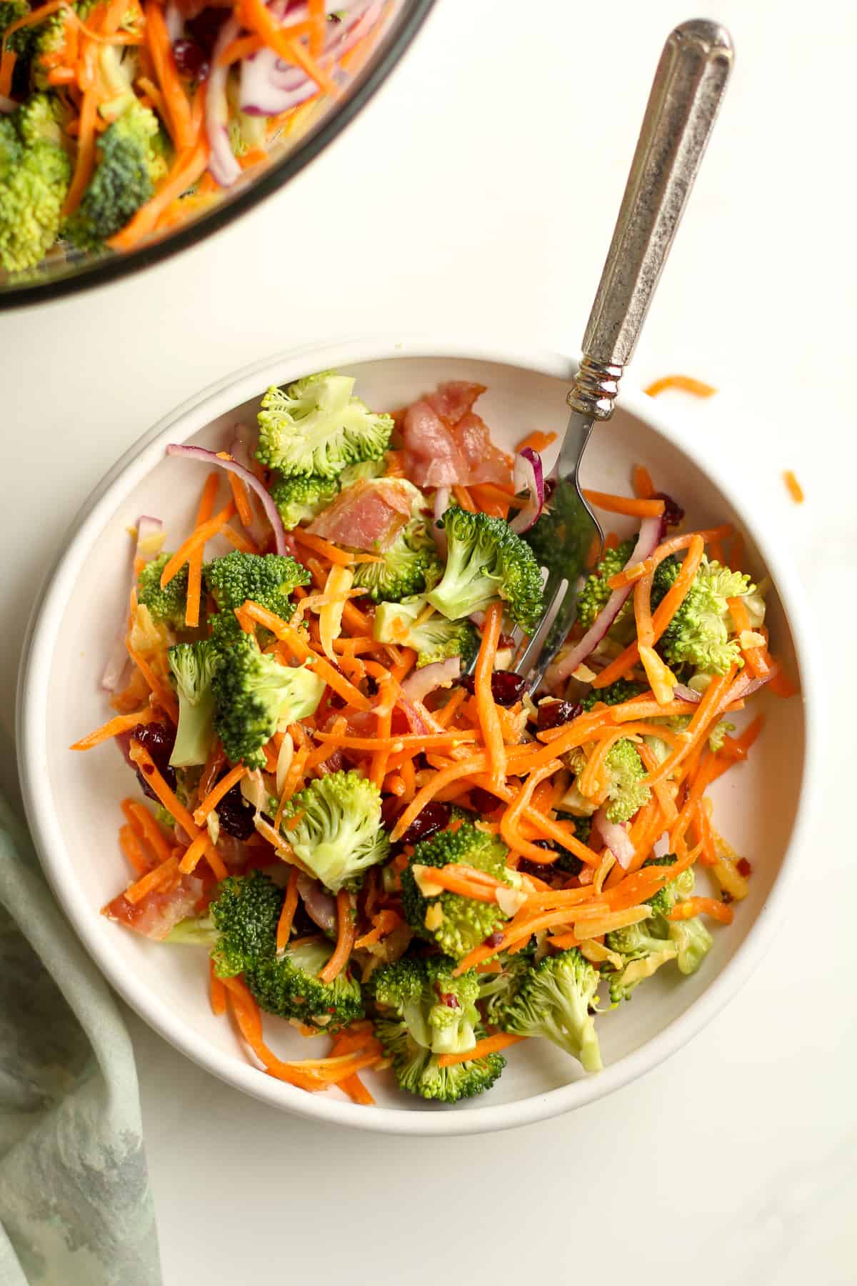 A serving bowl of the broccolis salad with a fork inside.