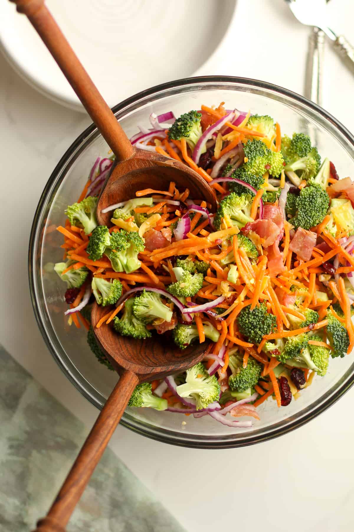 The broccoli salad with two wooden spoons inside.