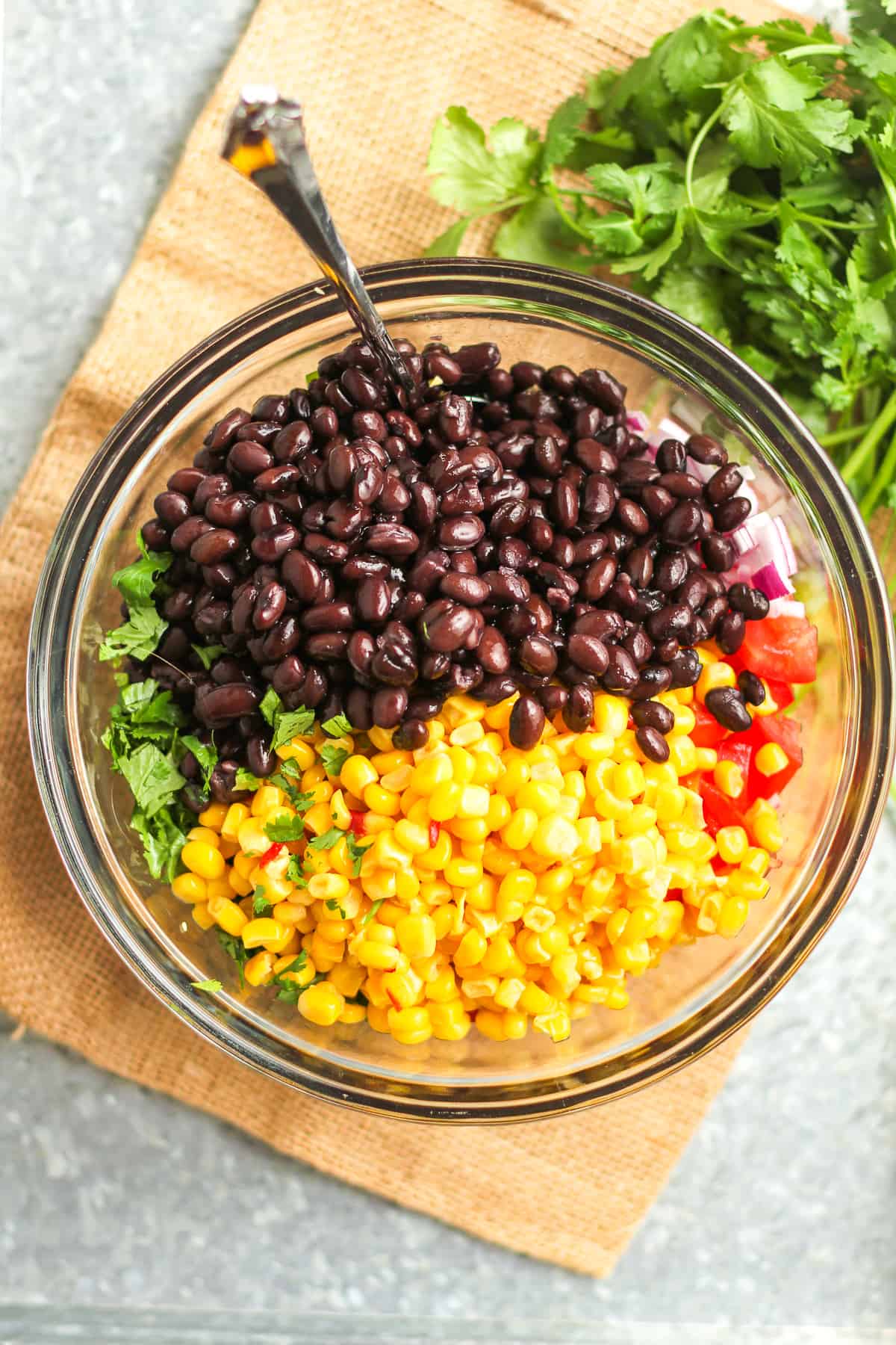 A glass bowl of the veggies with beans and corn on top.