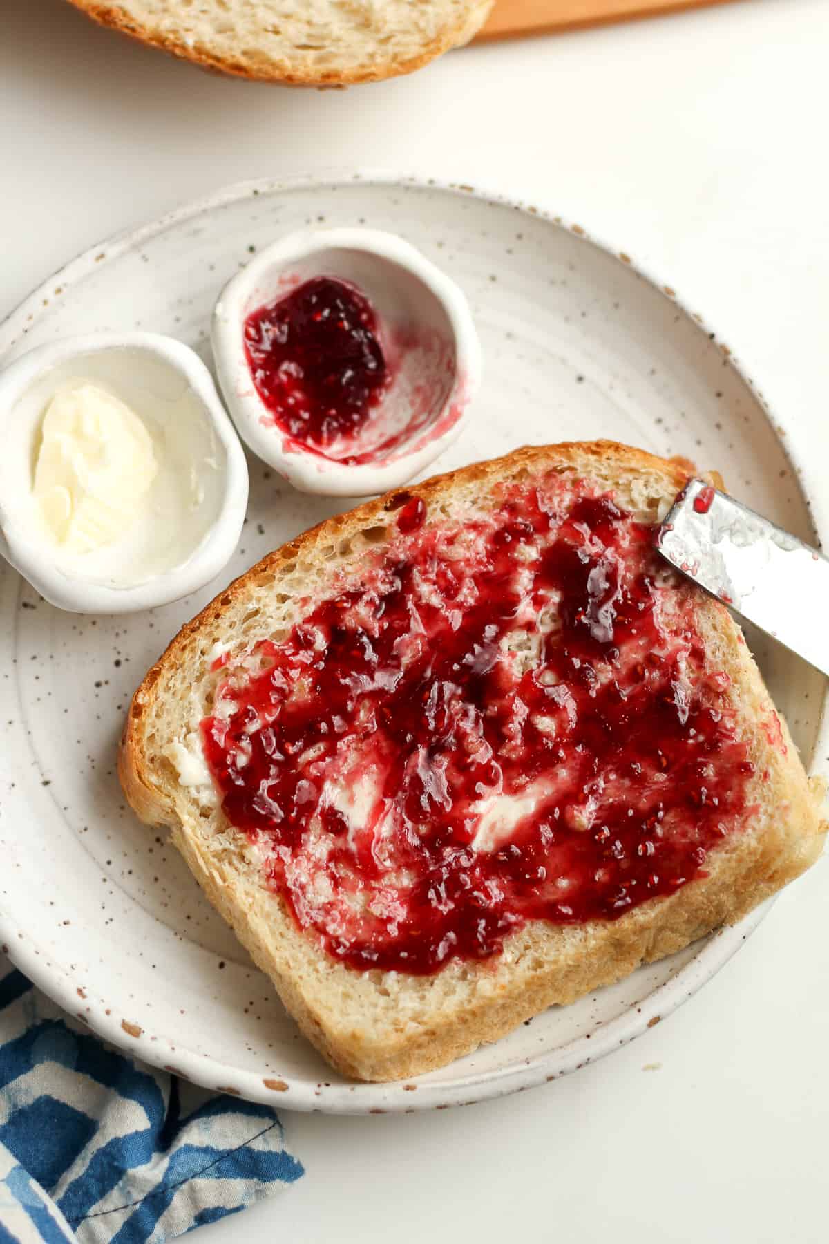 A plate of a piece of bread with butter and jelly.