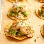 Side view of a pan of tostadas with refried beans, avocado, and grilled shrimp.