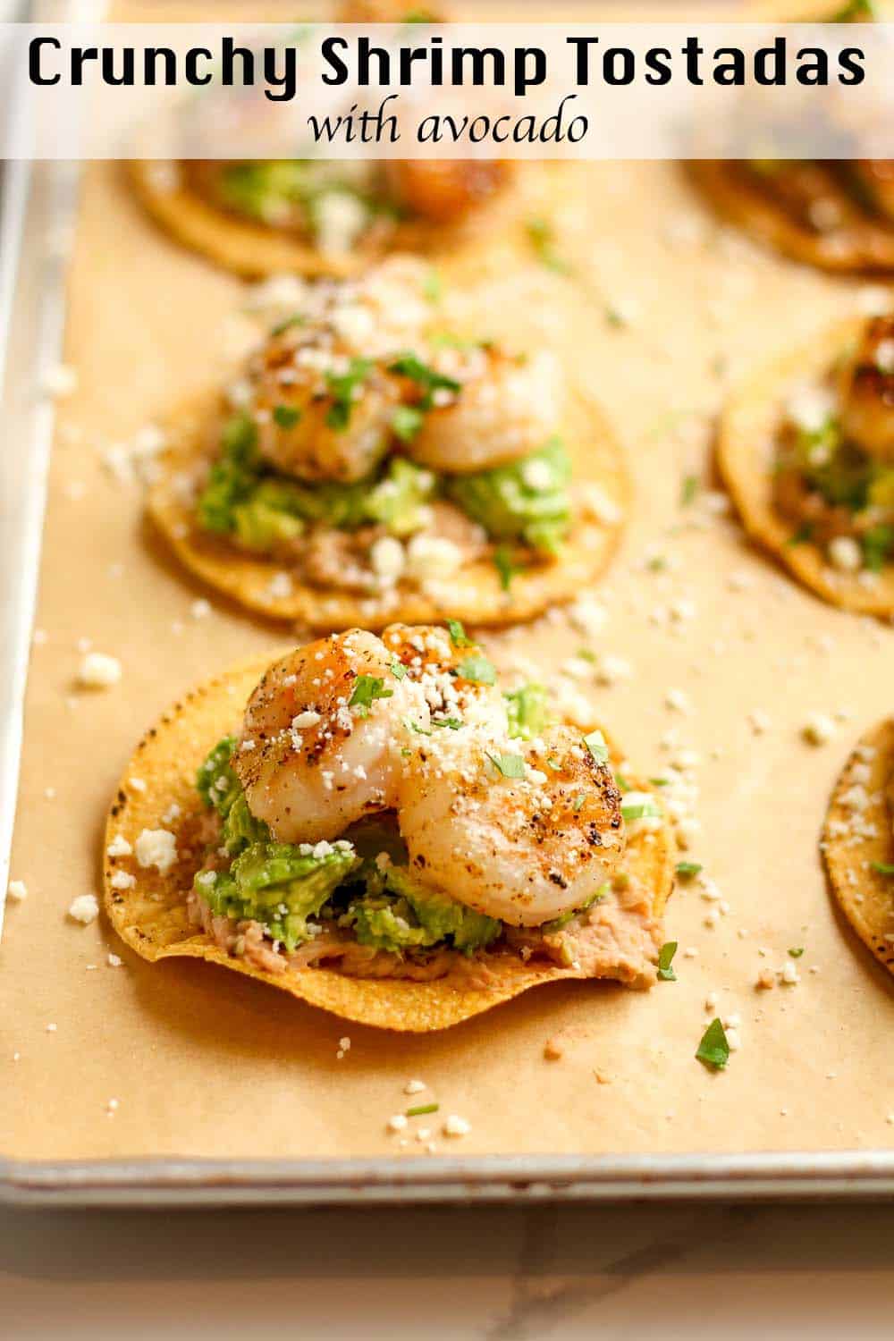 Side view of a pan of tostadas with refried beans, avocado, and grilled shrimp.