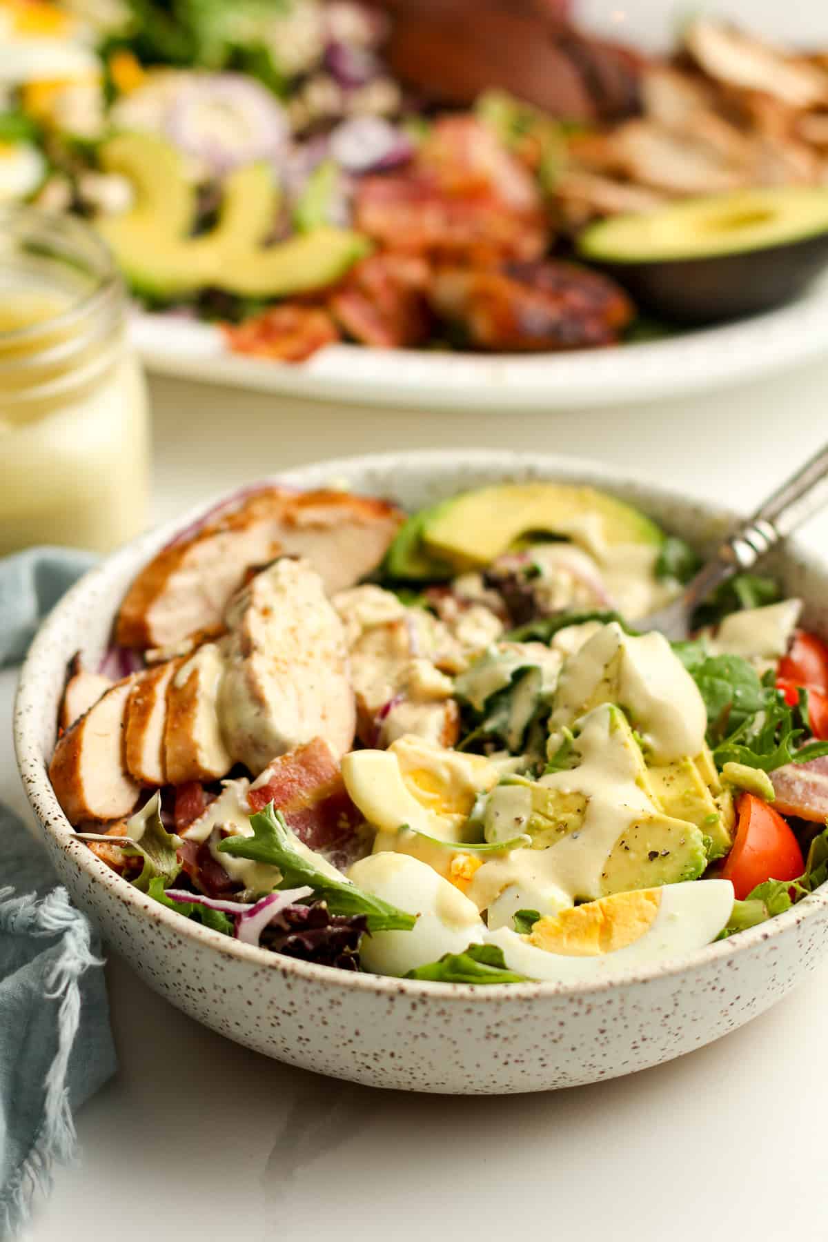 Side view of the salad with honey mustard on top, and the platter of salad in the background.