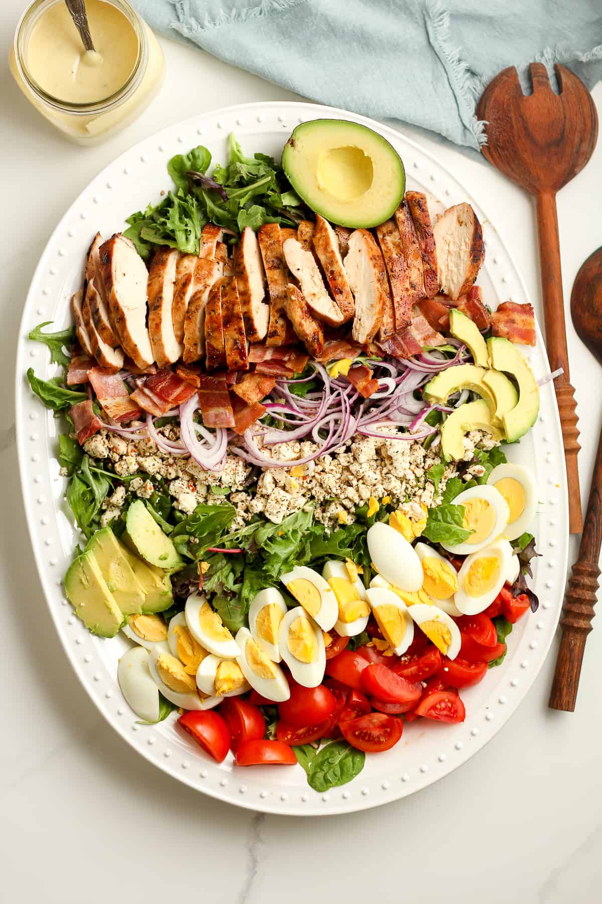 A large platter of the green salad, with rows of grilled chicken, feta cheese, eggs, tomatoes, etc.
