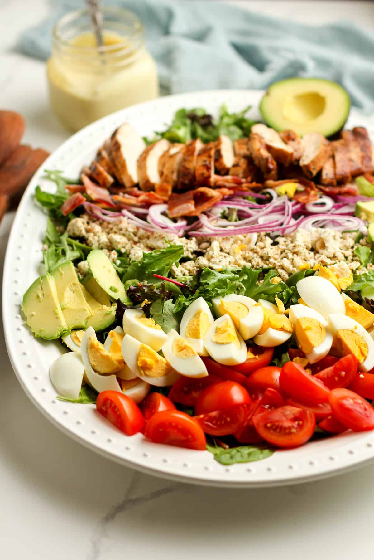 Side view of the platter of salad, with a jar of dressing.