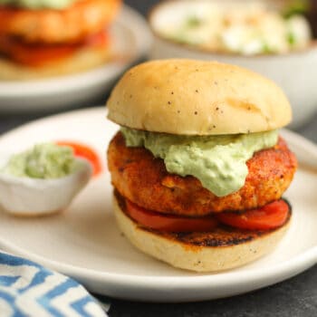 Side view of a grilled salmon burger with avocado cream.