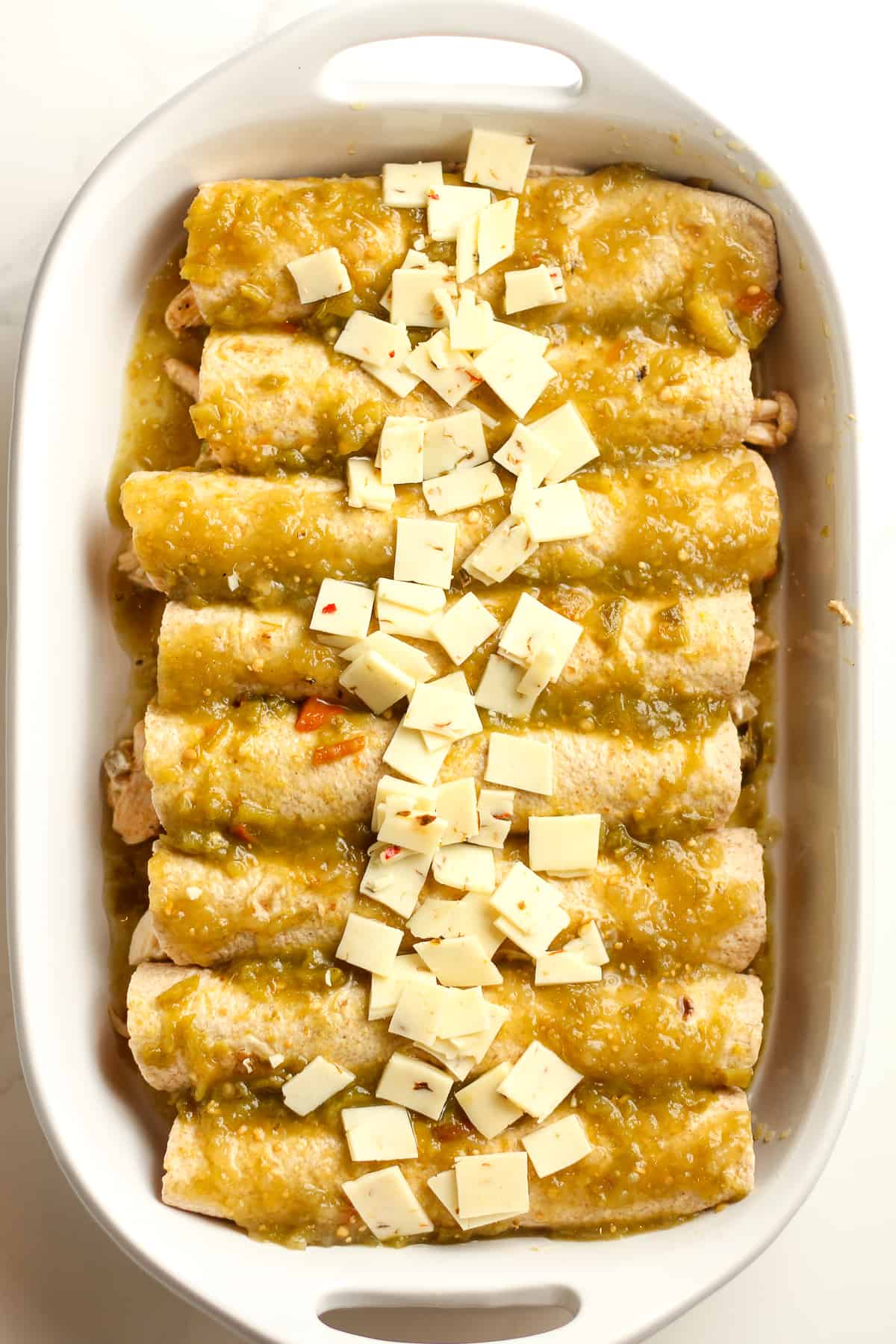 A casserole with 8 enchiladas on top, before baking.