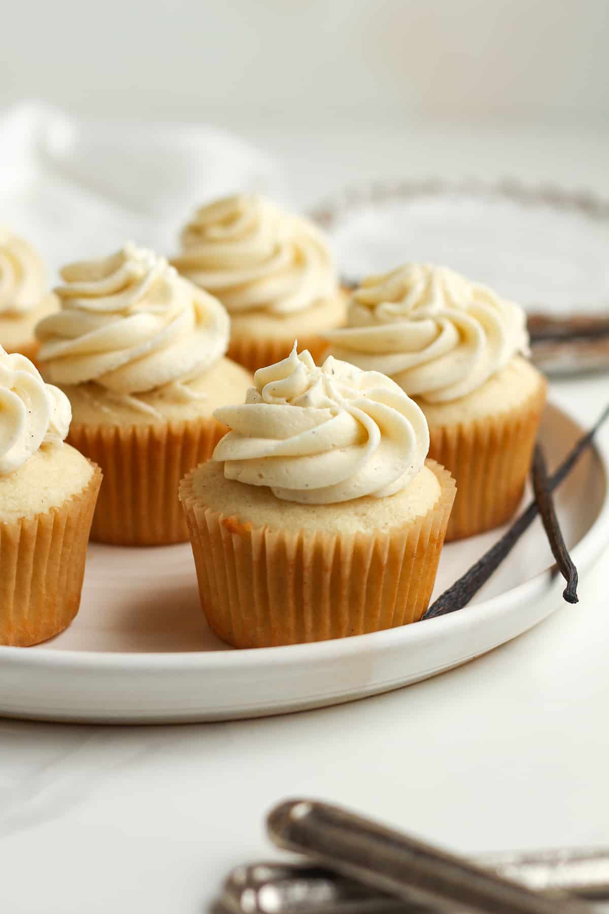 Side view of a plate of a vanilla bean cupcakes with vanilla buttercream.