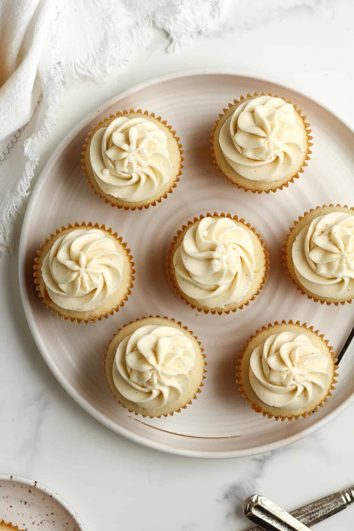 Overhead view of a plate of vanilla bean cupcakes with vanilla bean buttercream.