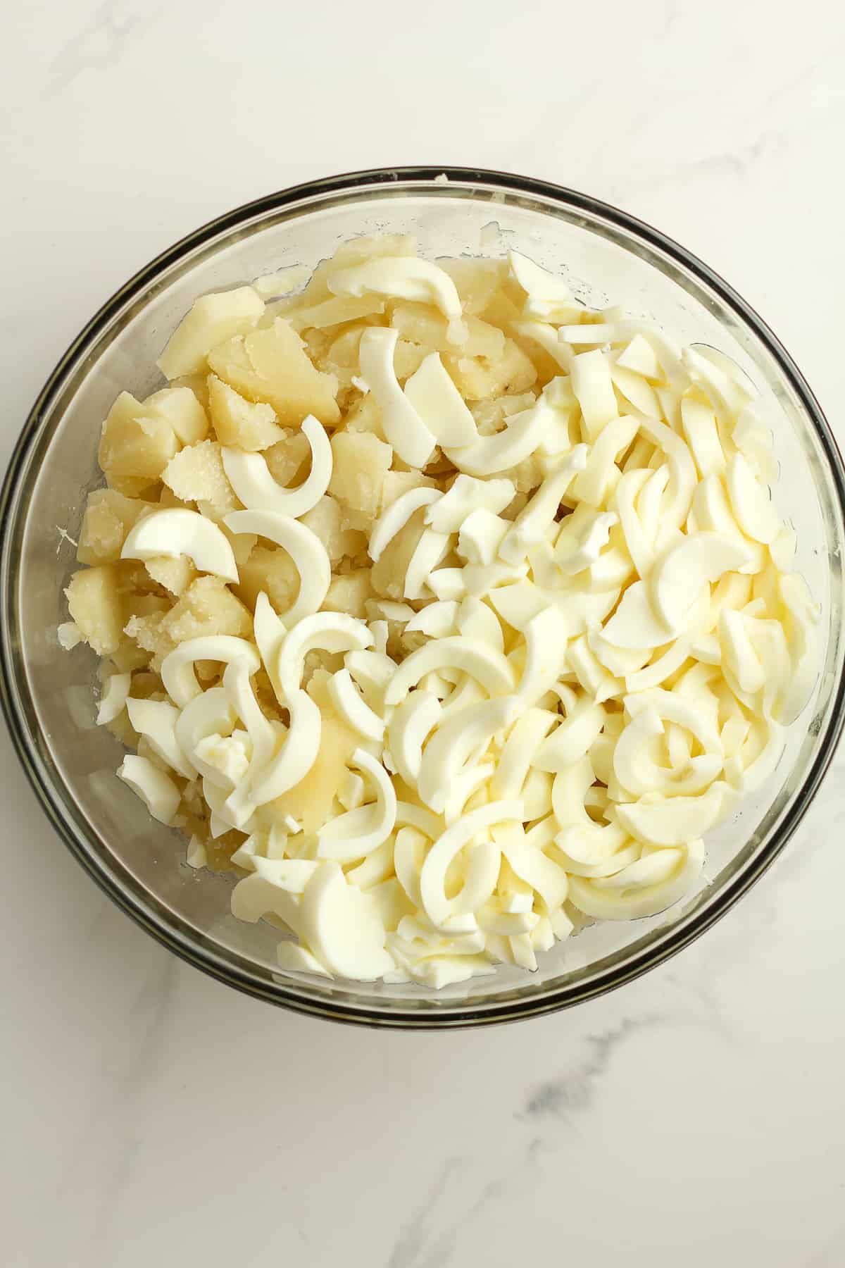 A bowl of the sliced potatoes topped with sliced egg whites.