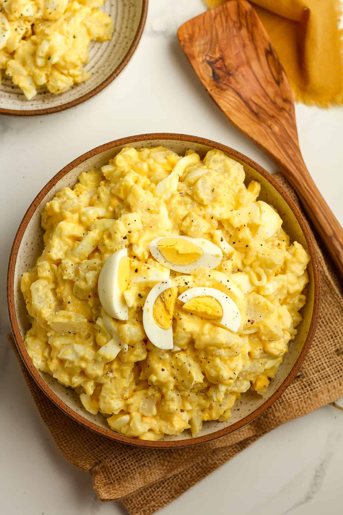 A large bowl of the creamy potato salad with a quartered egg on top.