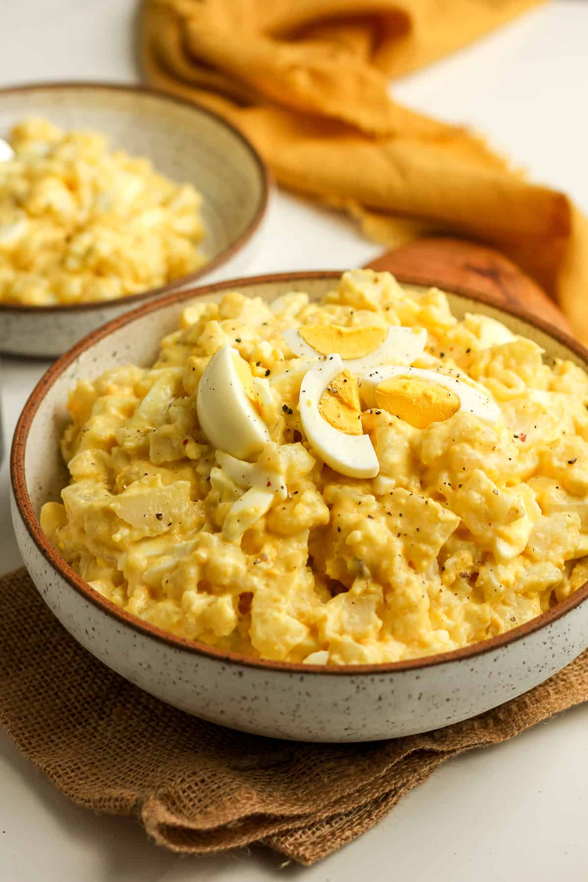 Side view of the bowl of potato salad with a serving in back of it.