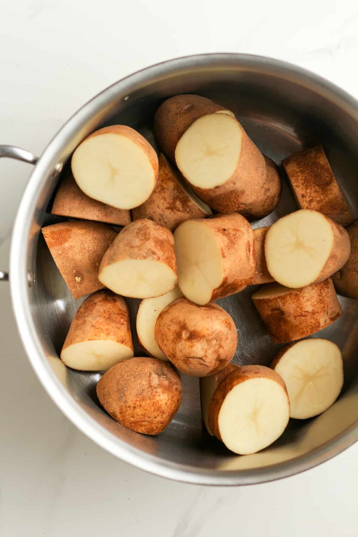 A pot of russet potatoes cut into thirds.