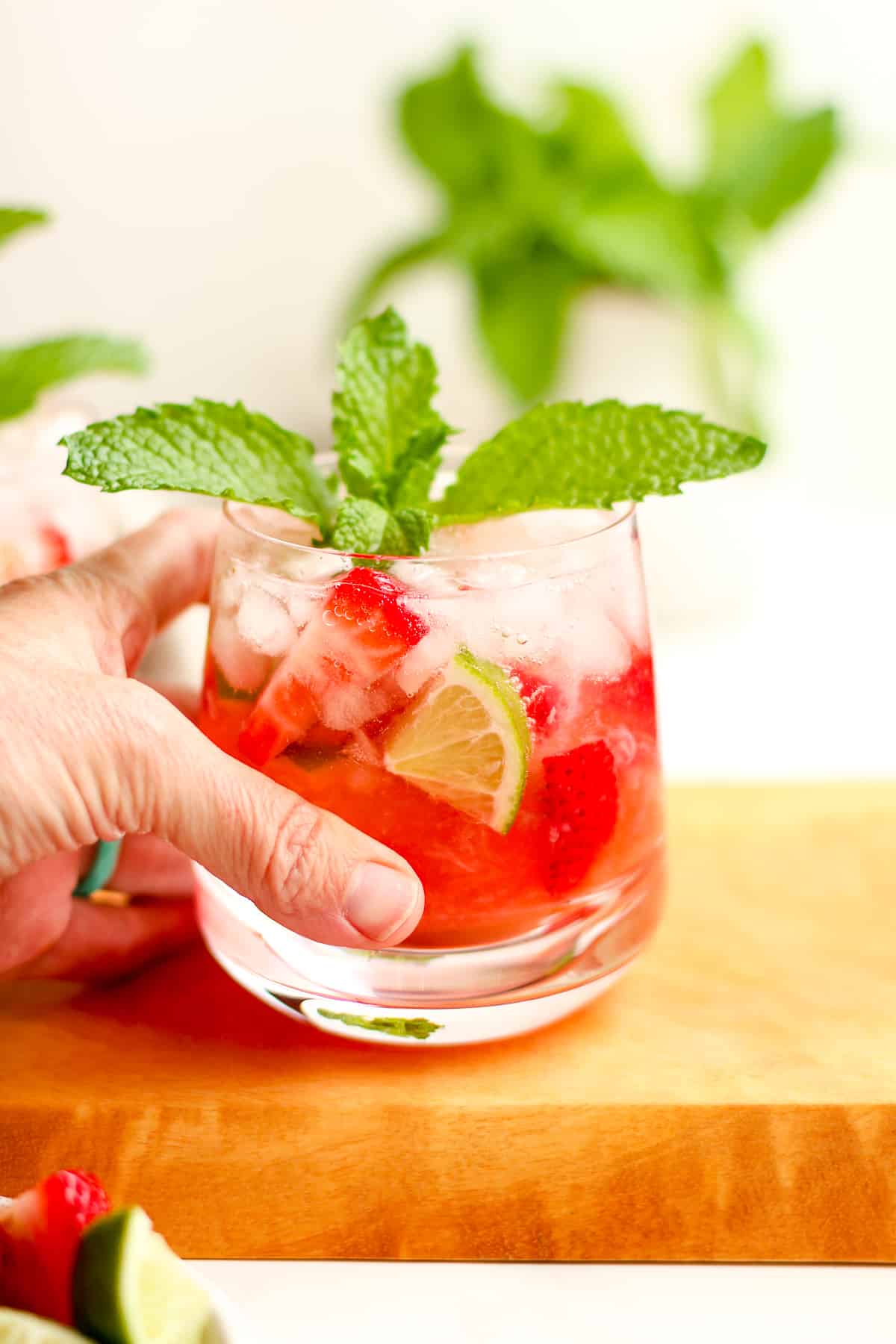 My hand reaching for a strawberry mojito.