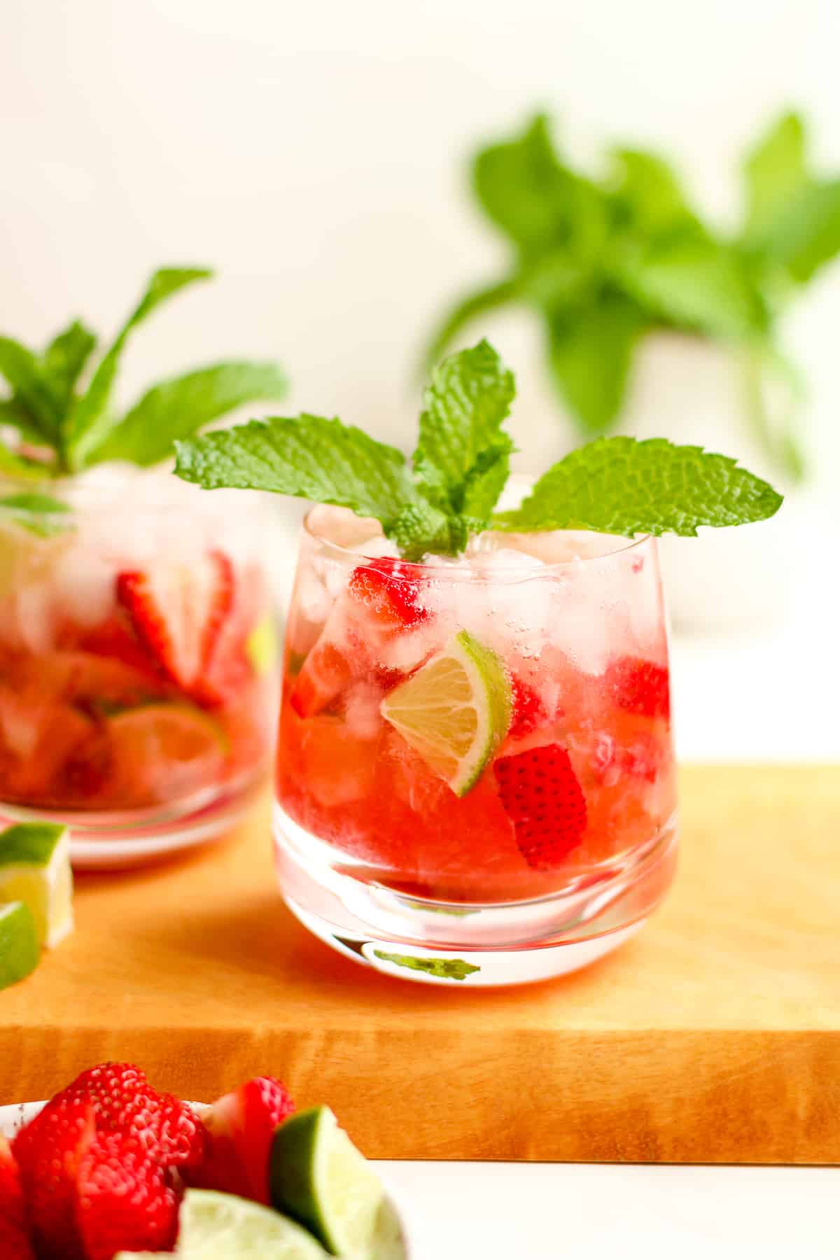 Side view of two glasses of strawberry mojitos with mint.