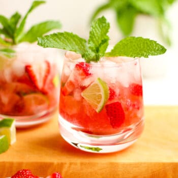 Side shot of two glasses of strawberry mojitos.