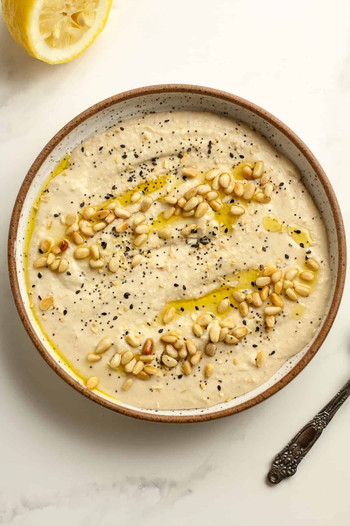 A bowl of the creamy hummus, with pine nuts on top.