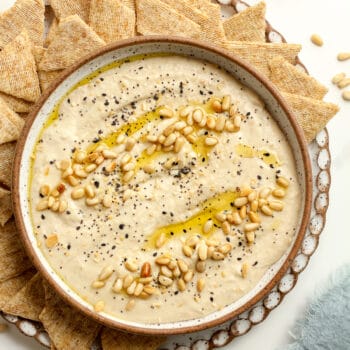 A bowl of creamy pine nut hummus with pine nuts and olive oil, plus everything bagel seasoning.