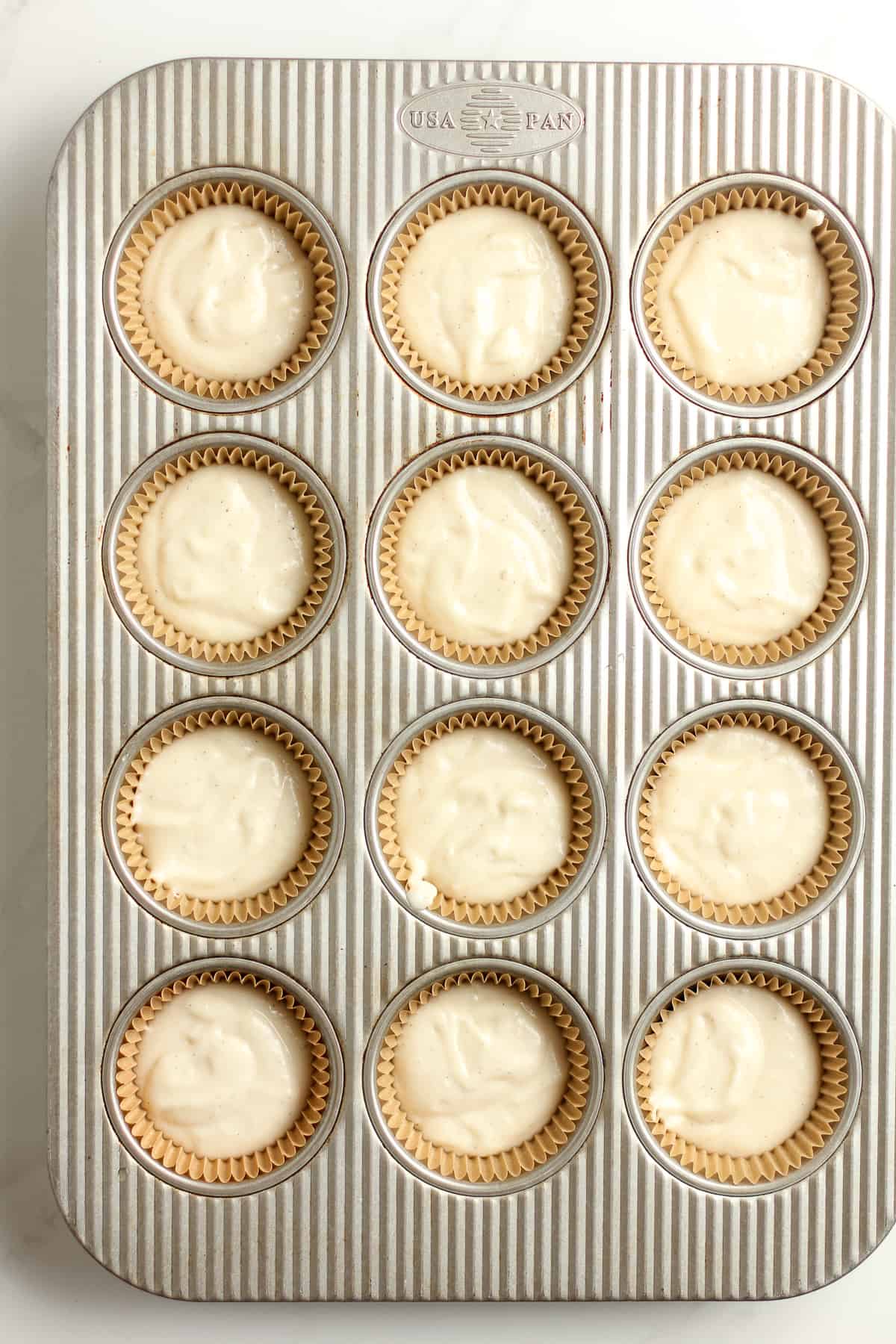 A 12-cup muffin tin with vanilla bean batter.
