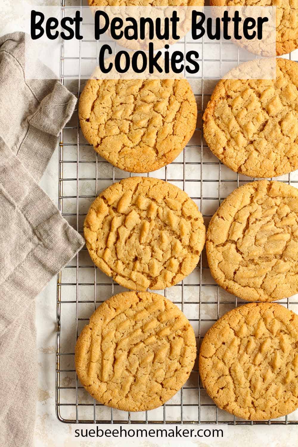 Eight peanut butter cookies on a cooling rack with a gray napkin.