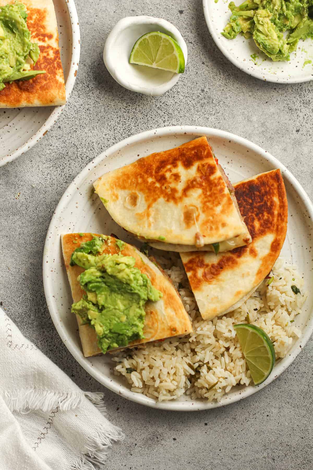 Overhead shot of a plate of quesadillas, with guacamole and rice.