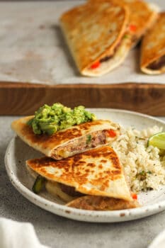 Side shot of a plate of two stacked quesadillas with rice.